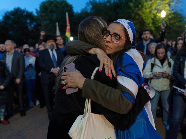 People embrace as they gather to light candles in a makeshift memorial to honor Yaron Lischinsky and Sarah Milgrim who were killed. Picture: AP