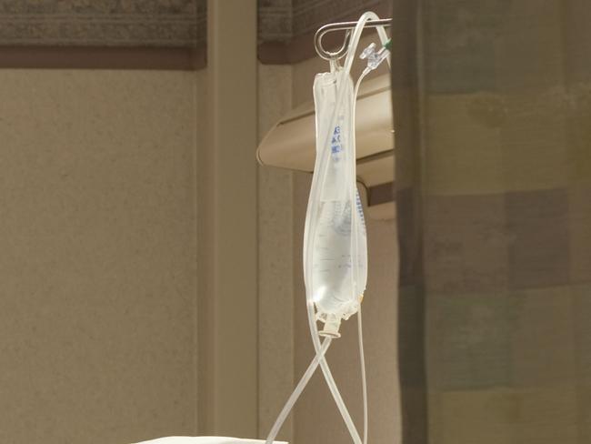 Vacant hospital bed in room with flowers and IV bag