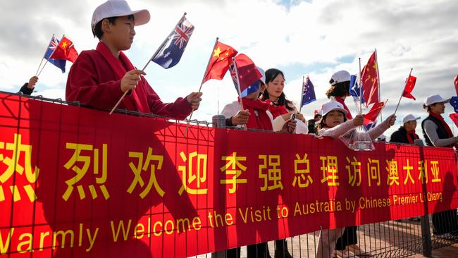 People wave Chinese national flags as they await the arrival of China's Premier Li Qiang in Adelaide. Picture; Getty Images.