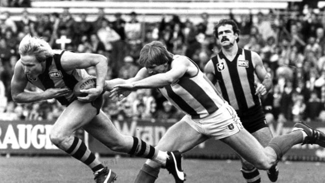 Peter Knights eludes North Melbourne’s Gary Cowton in 1983 as Leigh Matthews looks on. Picture: HWT