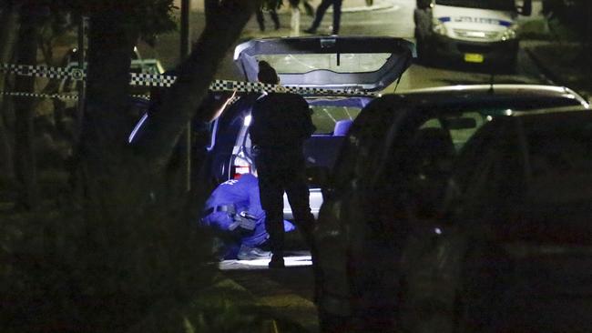 Police search a car at the scene of the arrest. Picture: Steve Tyson