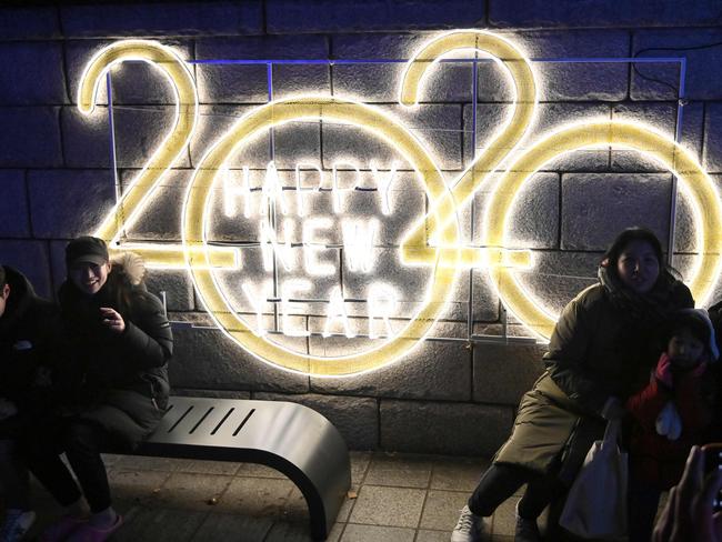 People pose for a picture in front of a 2020 luminous sign after midnight during a countdown event to mark the New Year in central Seoul. Picture: AFP