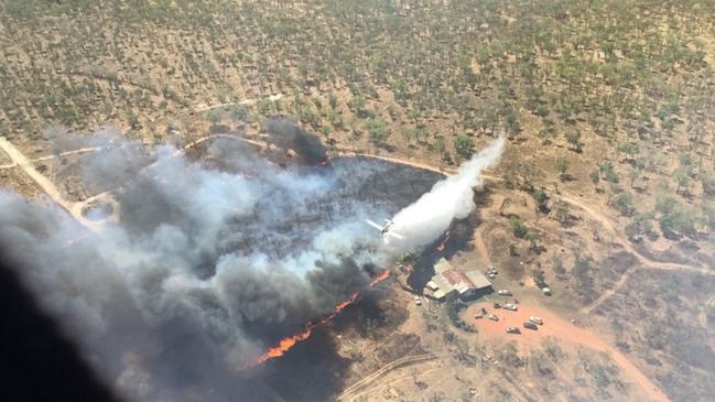 Aerial units carry out water bombing to protect properties as a fire front comes close to them. The fire is believed to have been deliberately lit, with police now questioning a man. Picture: Bushfires NT