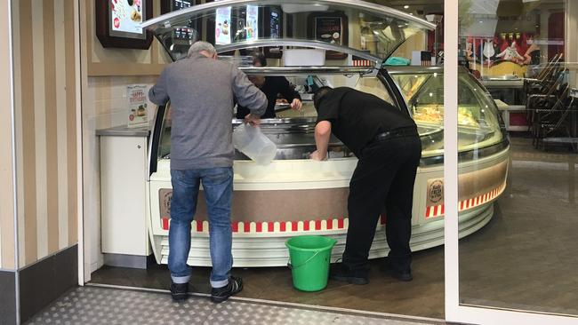 Workers clear melted ice cream from freezers at Gelatissimo. Picture: Matt Loxton