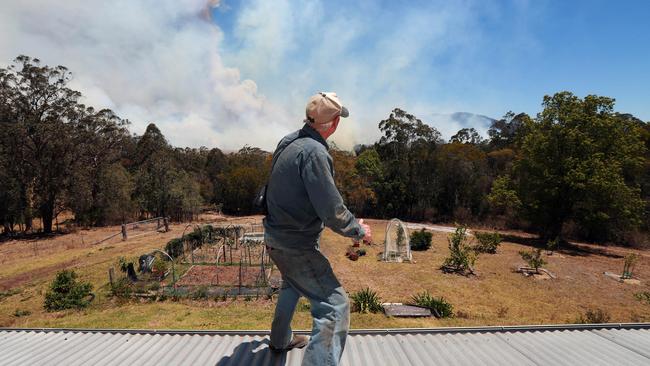 Barry Smith watches the fire approach from the vantage point of his roof. Picture: Gary Ramage