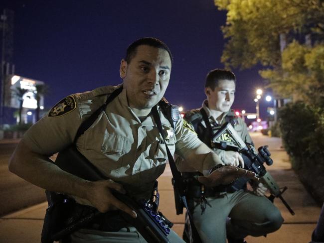 Police officers advise people to take cover near the scene of a shooting near the Mandalay Bay Resort. Picture: AP