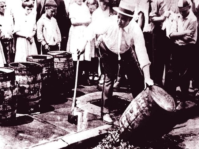 Man pouring illicit illegal liquor alcohol down drain during prohibition in the USA during the 1920s.