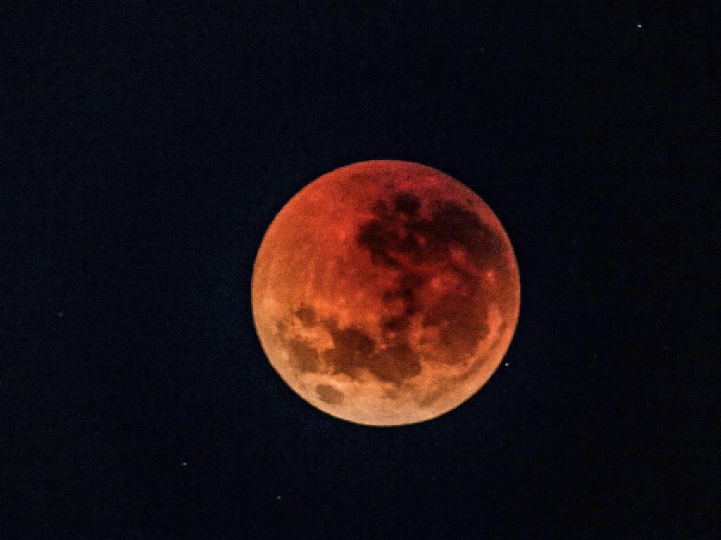 A ‘Super Blood Moon’ as seen from underneath Sydney's Harbour Bridge in 2018. As the eclipse reaches its peak, refracted light from the sun causes the moon to appear red. Picture: Nicholas Eagar