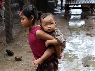 A young Myanmar refugee carrying her sibling