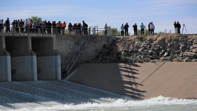 Locals gather on the regulator for as the first water to hit the Menindee Lake in three years pours into the storage