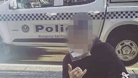 An eshay poses in front of a SA Police vehicle.