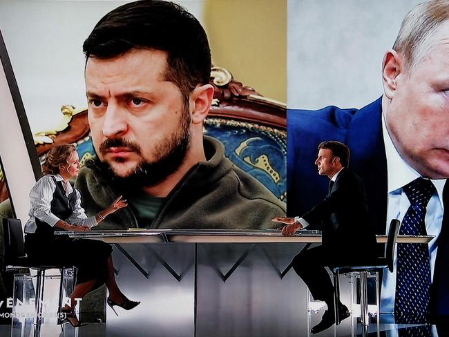 TOPSHOT - French president Emmanuel Macron (R) speaks during an interview by French journalist and TV host Caroline Roux (L) in front of pictures of Ukrainian President Volodymyr Zelensky and Russian President Vladimir Putin as part of a new show entitled "L'evenement", in Saint-Denis, northern Paris, on October 12, 2022. - Emmanuel Macron is to give an hour-long interview on France 2, devoted to international crises and France's place in the world: on October 12, 2022 evening, he will take part in an unprecedented exercise, dictated by the escalation of the war in Ukraine and its heavy repercussions on Europe and the French. (Photo by Ludovic MARIN / AFP)