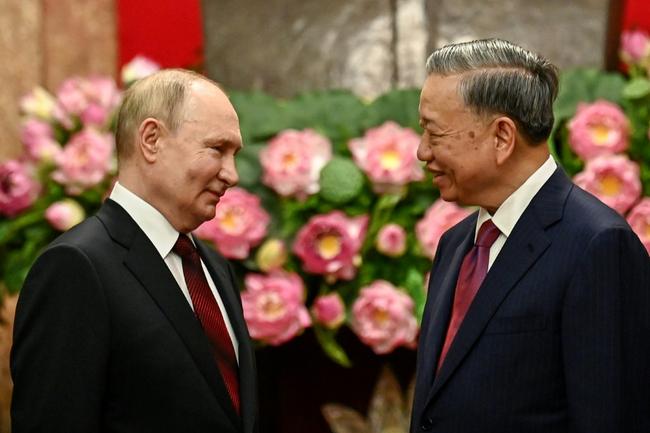 Russian President Vladimir Putin (L) is greeted by his Vietnamese counterpart To Lam at the Presidential Palace in Hanoi on Thursday