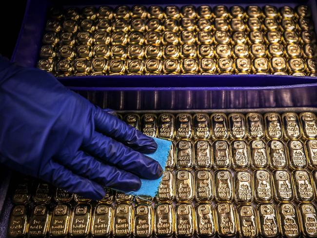 (FILES) A worker polishes gold bullion bars at the ABC Refinery in Sydney on August 5, 2020. Gold prices soared to a record high above USD 2,100 on December 4, 2023 as traders grow increasingly confident the Federal Reserve will cut interest rates in the new year. (Photo by DAVID GRAY / AFP)