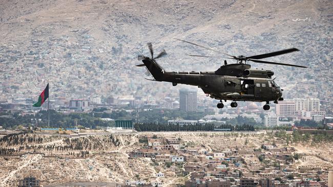 A British Puma helicopter flies over Kabul; a broken-down truck is winched on to a RAF C-17 Globemaster; a military policewoman documents boxes due to be sent back to the UK. Picture: Getty Images