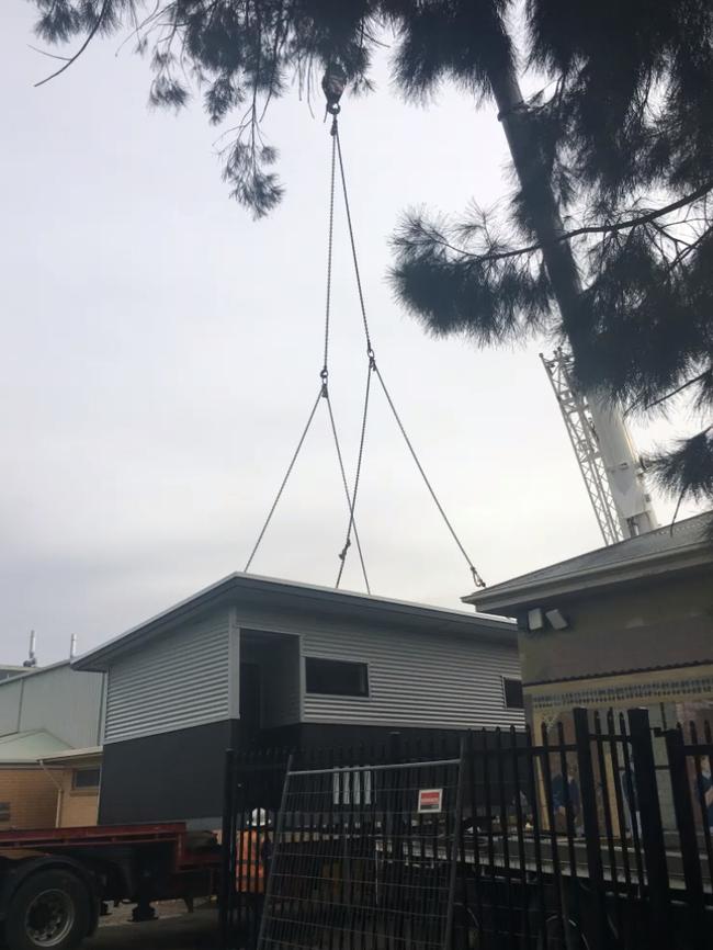 A crane lowers one of the demountables onto a tennis court. Picture: Mitcham Girls High