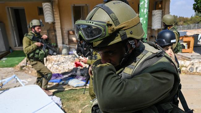 An Israeli soldier covers his nose to block out the stench of dead bodies in the kibbutz. Picture: Getty Images