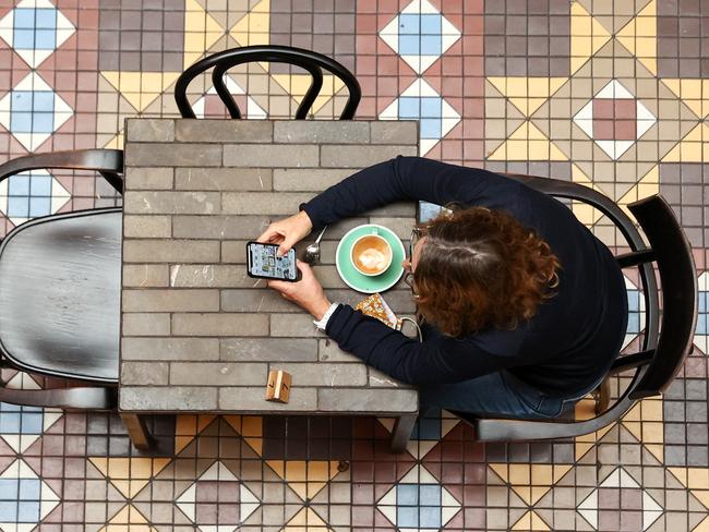 A diner uses a phone at a cafe in Strand Arcade in Sydney, Australia, on Monday, Oct. 11, 2021. Residents of New South Wales who have received both doses of the covid vaccine were on Monday again allowed to start visiting non-essential retail stores, pubs and gyms, with capacity limits. The government eased lockdown measures once 70% of people over age 16 were fully vaccinated. Photographer: Brendon Thorne/Bloomberg via Getty Images