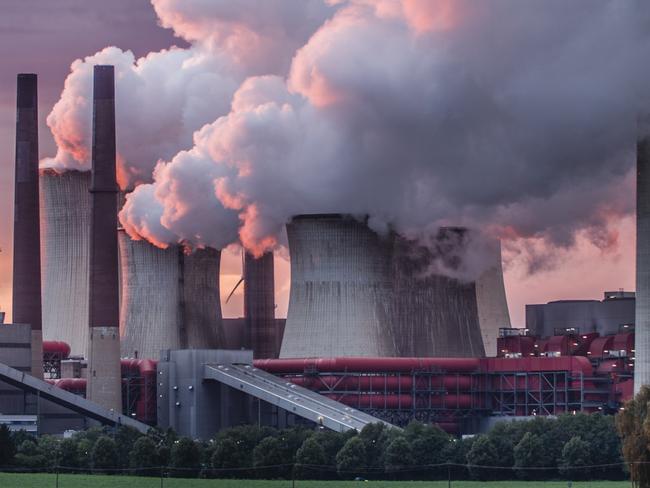 Industry in dramatic red sunset light. Chimneys and cooling tower of a coal fired power station.