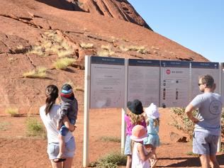 Tourists reading the Anangu plea to stay off Uluru. Photo: ZACH HOPE