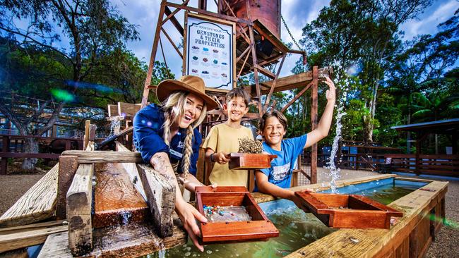 Madi Roberts (left) helps Ishai, 9 and Jonah Angel, 14, search for gemstones at the new Currumbin Wildlife Sanctuary precinct Outback Springs. Picture: Nigel Hallett