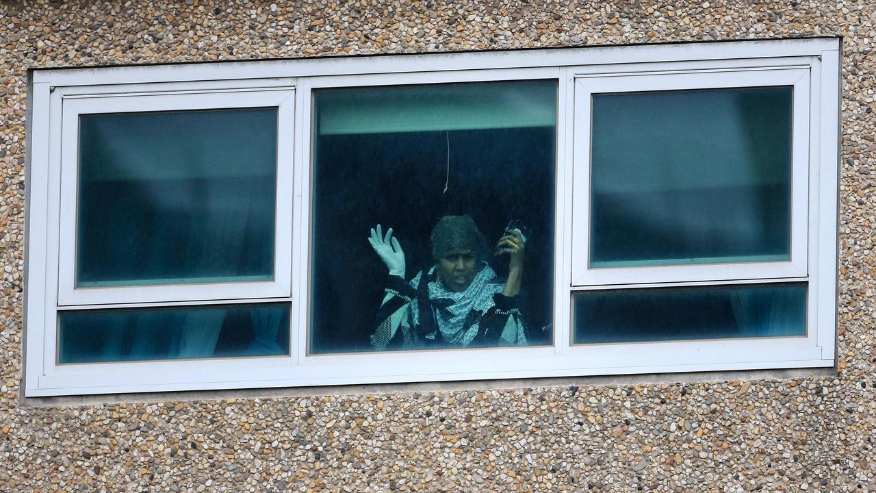 A women looks out of her window in the Tower at 120 Flemington Rd, one of the housing blocks placed into hard lockdown. Picture: Sarah Matray