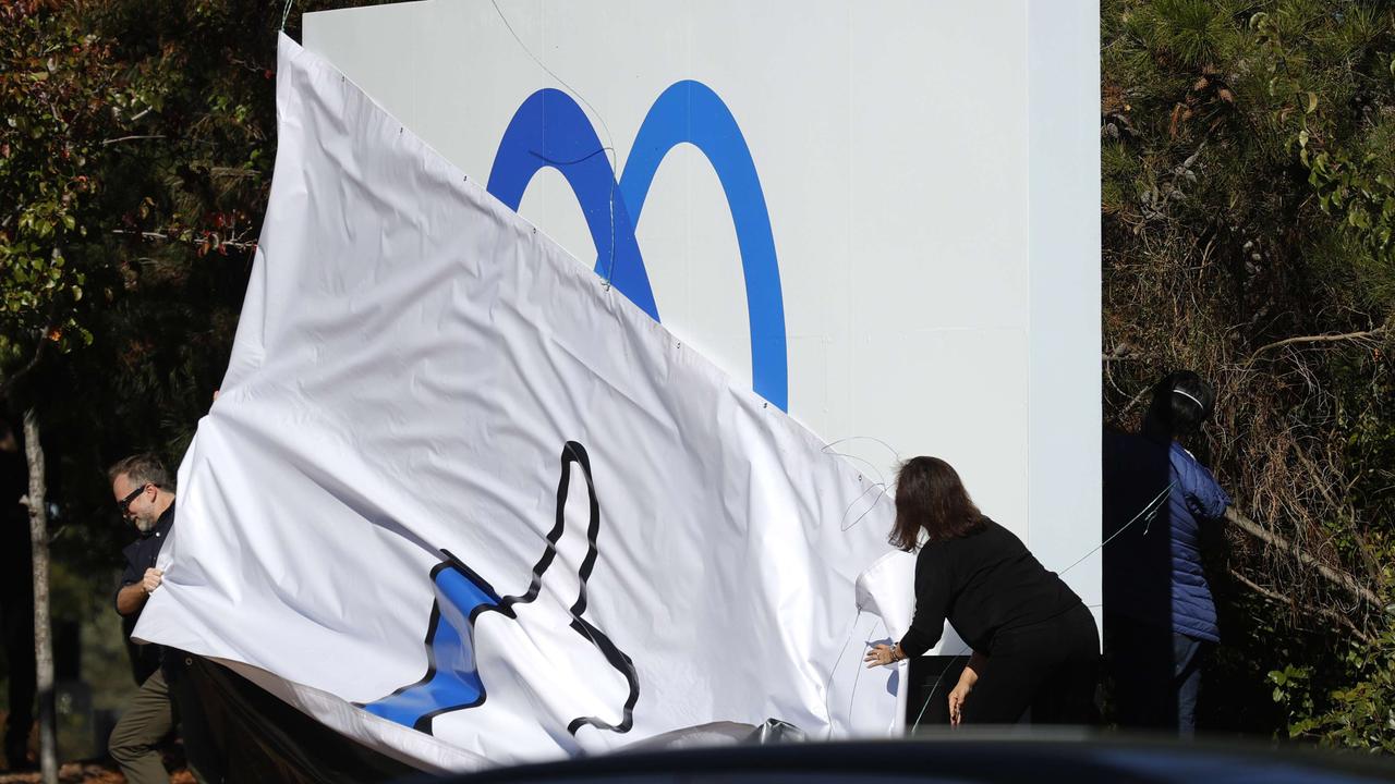 Facebook employees unveil a new logo and the name 'Meta' on the sign in front of Facebook headquarters in Menlo Park, California.