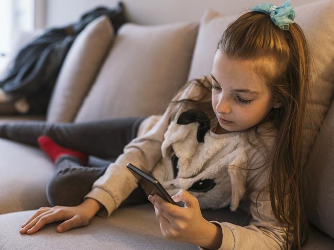 Portrait of serious teenage girl ling on bed and using smartphone. technology, internet, communication and people concept. Photo of pensive Caucasian Teenage Girl Sending Text Message Whilst Lying In Bed during the day