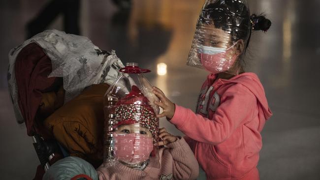 Children wear plastic bottles in a bid to protect themselves from the coronavirus in Beijing. Picture: Getty Images