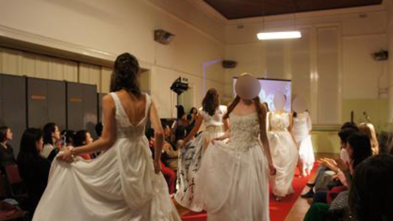 Providence members wearing bridal dresses at a modelling convention.