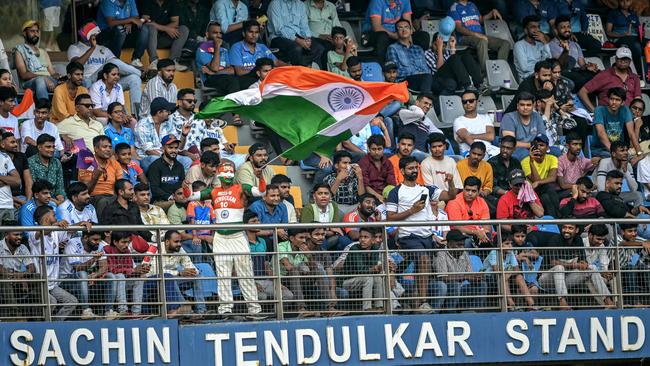 A fan waves Indian national flag while watching the first day of the third Test cricket match between India and New Zealand at the Wankhede Stadium in Mumbai on November 1. Picture: AFP