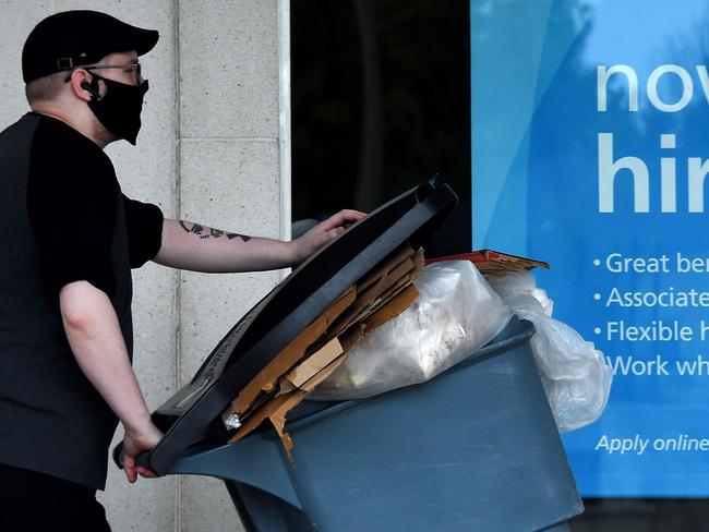 A man wearing a face mask walks past a sign "Now Hiring" in front of a store amid the coronavirus pandemic in Arlington, Virginia. Picture: Getty Images