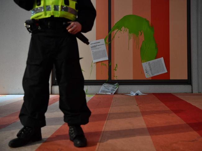 A police officer stands near pamphlets and green paint which were thrown by climate activists at the exterior of the headquarters of energy company Scottish Power in Glasgow during the COP26 UN Climate Change Conference. Picture: AFP