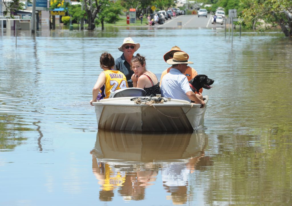 A family is boated across the swollen creek at Schultz Bridge Tinana where many houses are flooded and families isolated. Photo: Robyne Cuerel / Fraser Coast Chronicle. Picture: Robyne Cuerel