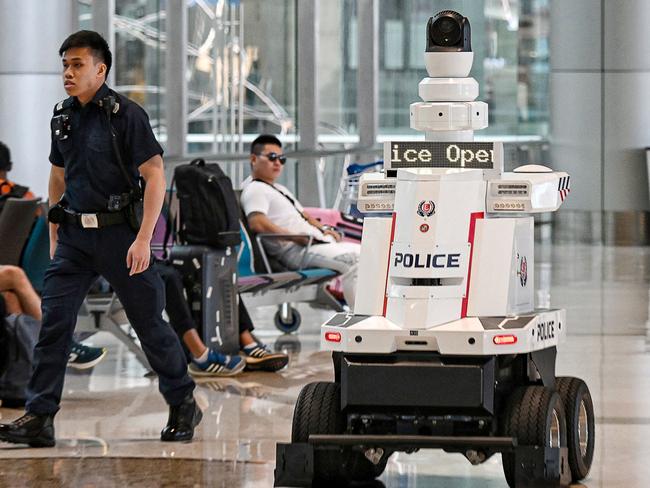 TOPSHOT - Singapore Police Force (SPF) officers patrol with a police robot at Changi Airport in Singapore on June 15, 2023. Singapore will "progressively deploy" more patrol robots across the city-state, police said on June 15, 2023, after more than five years of small-scale trials. (Photo by Kua Chee Siong / The Straits Times / AFP) / Singapore OUT / -- IMAGE RESTRICTED TO EDITORIAL USE - STRICTLY NO COMMERCIAL USE --