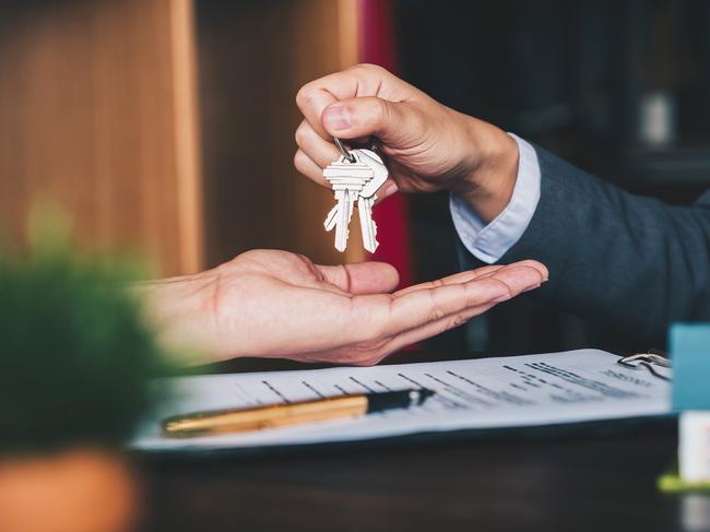 estate agent giving house keys to woman and sign agreement in office