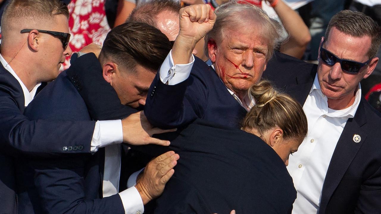 A defiant US Republican candidate Donald Trump is seen surrounded by secret service agents as he is taken off the stage after being injured by gunfire at a campaign event at Butler Farm Show Inc. in Butler, Pennsylvania, on July 13, 2024. Picture: AFP