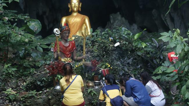 Family members pray in front of a Buddhist statue near the cave. Picture: AP.