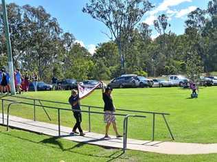 Gympie Cats life member Ray Warren and Cats midfielder Lanze Magin unveil the 2018 Wide Bay Premiership Flag to the supporters at their first home game of 2019. Picture: Bec Singh