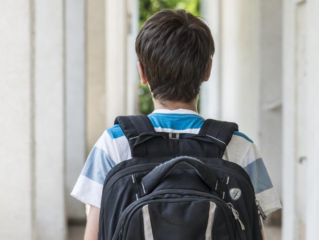 Teenage school boy with a backpack walking to school