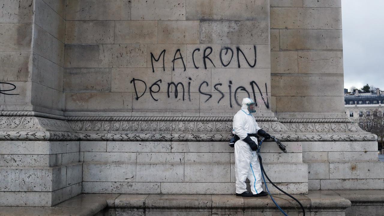 A worker is about to clean a graffiti reading " Macron resignation" on the Arc de Triomphe the day after a demonstration, in Paris. Picture: AFP