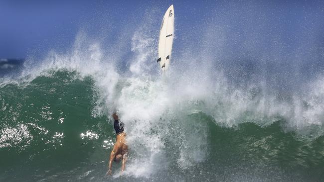 A surfer goes ‘lobster diving’ as he wipes out in wild waves at Snapper Rocks, as most south east Queensland beaches remain closed. Picture: Adam Head