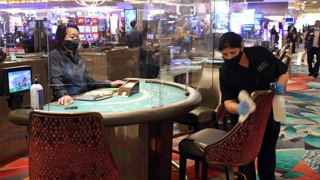 A dealer looks on as a cleaner sanitises the chairs at a blackjack table at Bellagio Resort &amp; Casino. Picture: AFP