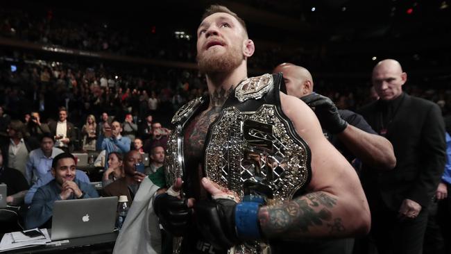 Conor McGregor leaves the octagon with his title belts after knocking out Eddie Alvarez.