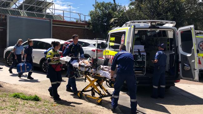 A man is taken to an ambulance outside the Andrew 'Boy' Charlton Aquatic Centre in Manly. Picture: Julie Cross