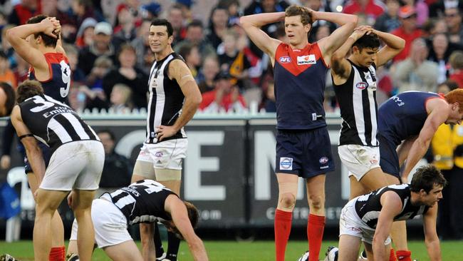 Melbourne and Collingwood players react after drawing in 2010.