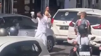 A Balinese priest lost his cool after a foreigner yelled insults. The priest stopped the traffic and ripped off his hat to attack the tourist. Picture: Instagram