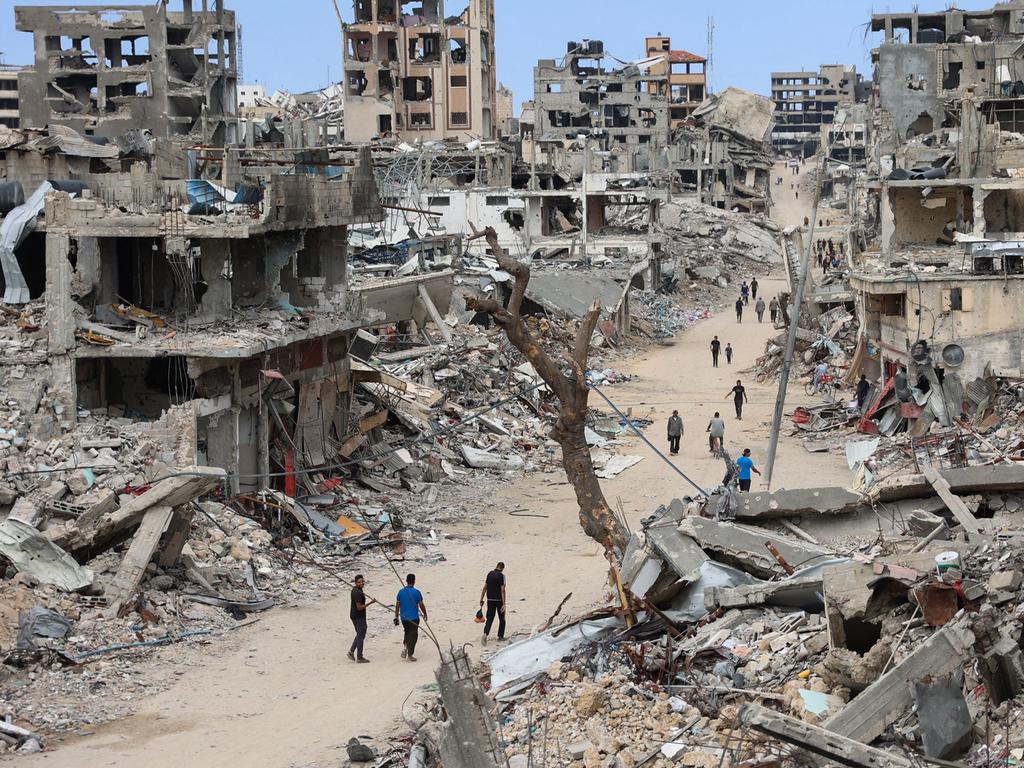 Palestinians walk on a dirt road lined with rubble from destroyed buildings in the Shujaiya neighbourhood of Gaza City. Picture: AFP