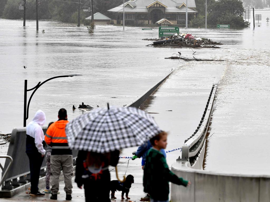 Residents look out toward flooded buildings next to the old Windsor Bridge earlier this month. Picture: AFP