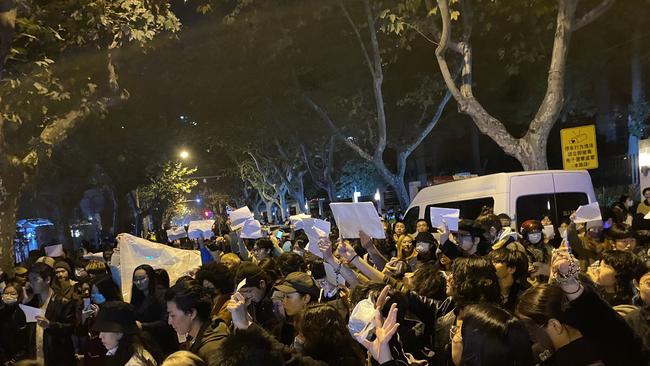 The protesters sang China’s national anthem and held up sheets of blank white paper, a popular symbol of resistance in China.